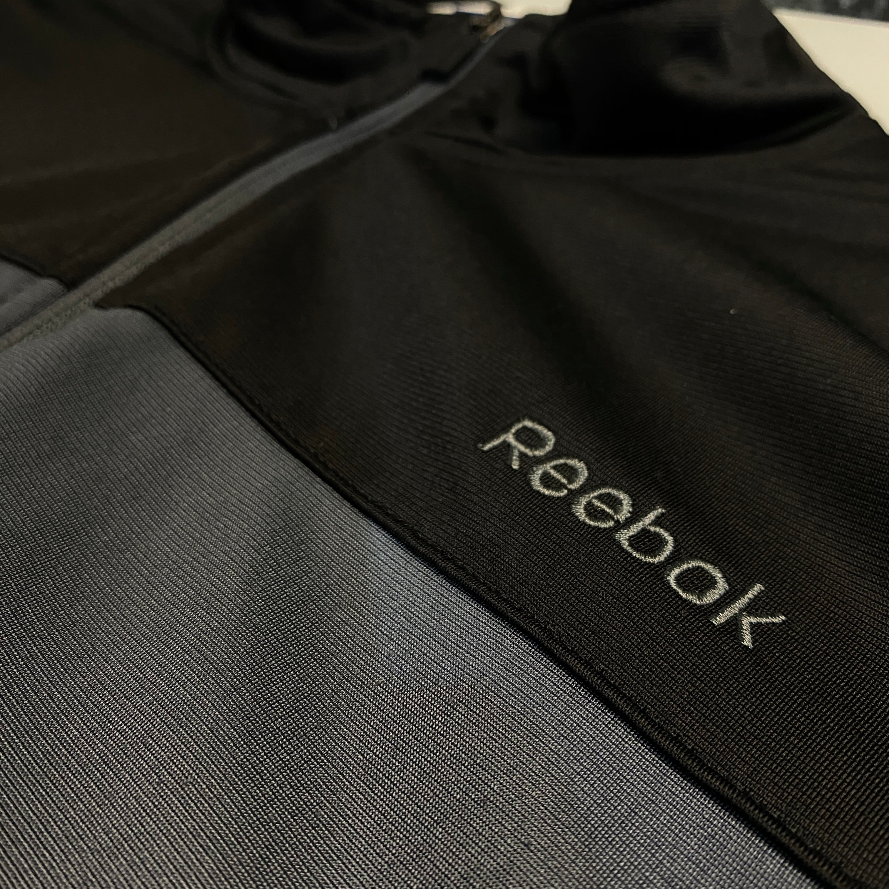 CHAQUETA REEBOK NEGRA CON PANEL AZUL Y GRIS